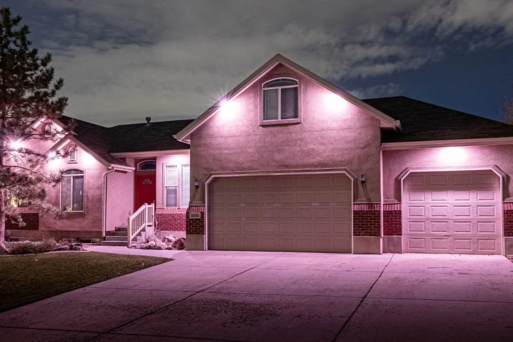 Home at night with pink downlights over the garage and entry