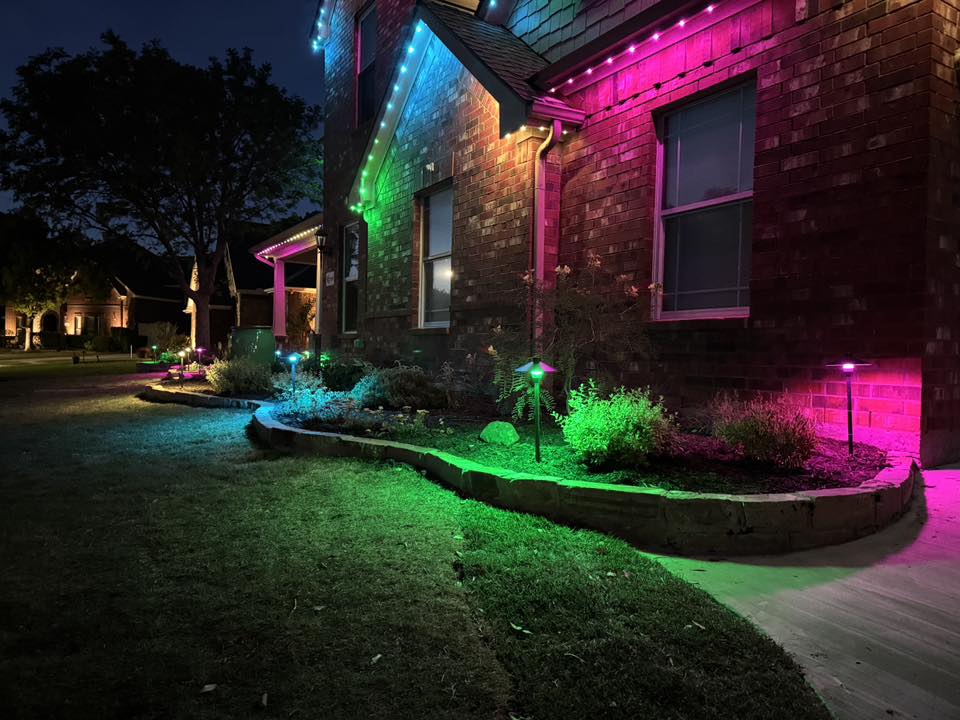 Brick home at night with green, blue and pink landscape and accent lighting