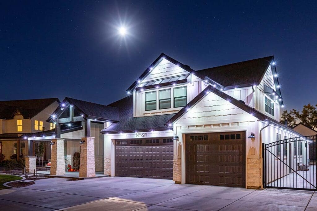 Two-story home at night with bright white accent lights on every roofline