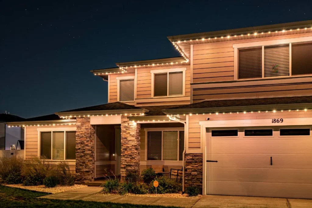 Two-story home at night with warm white accent lights along the roofline