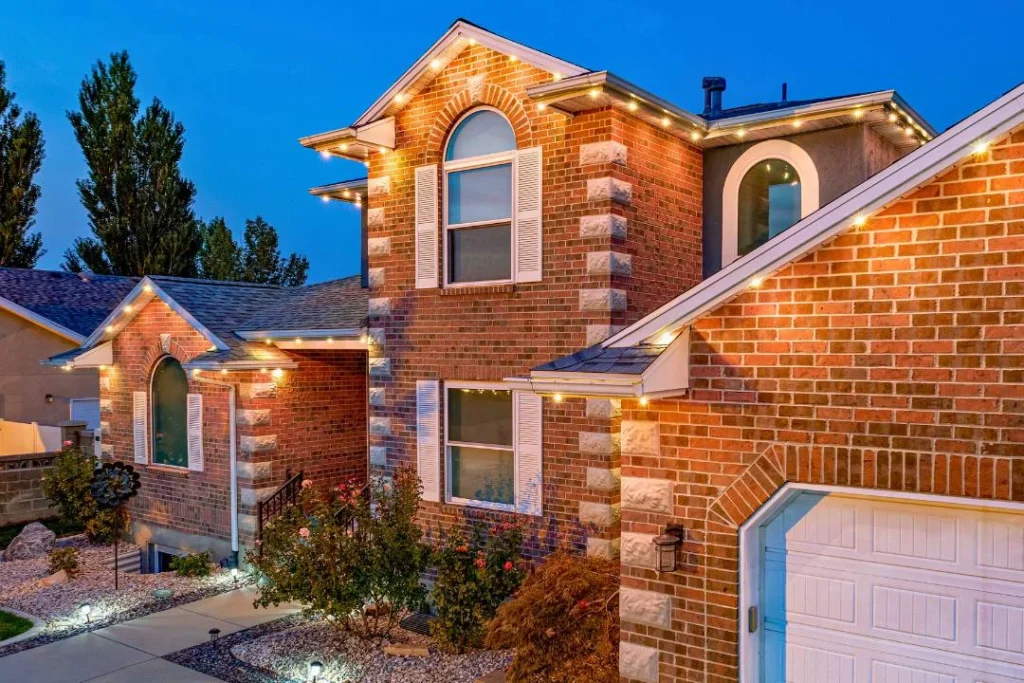 Brick home at dusk with bright white permanent roofline lights