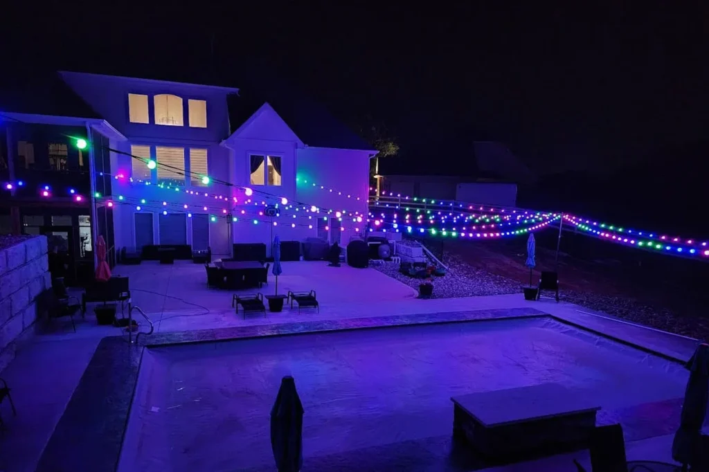 Backyard patio and home at night under multicolor globe string lights