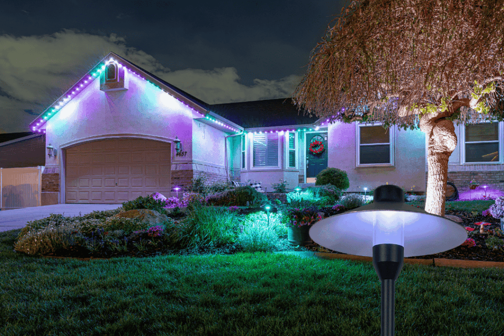 Home at night with blue and purple roofline lights and a pathway light in the yard