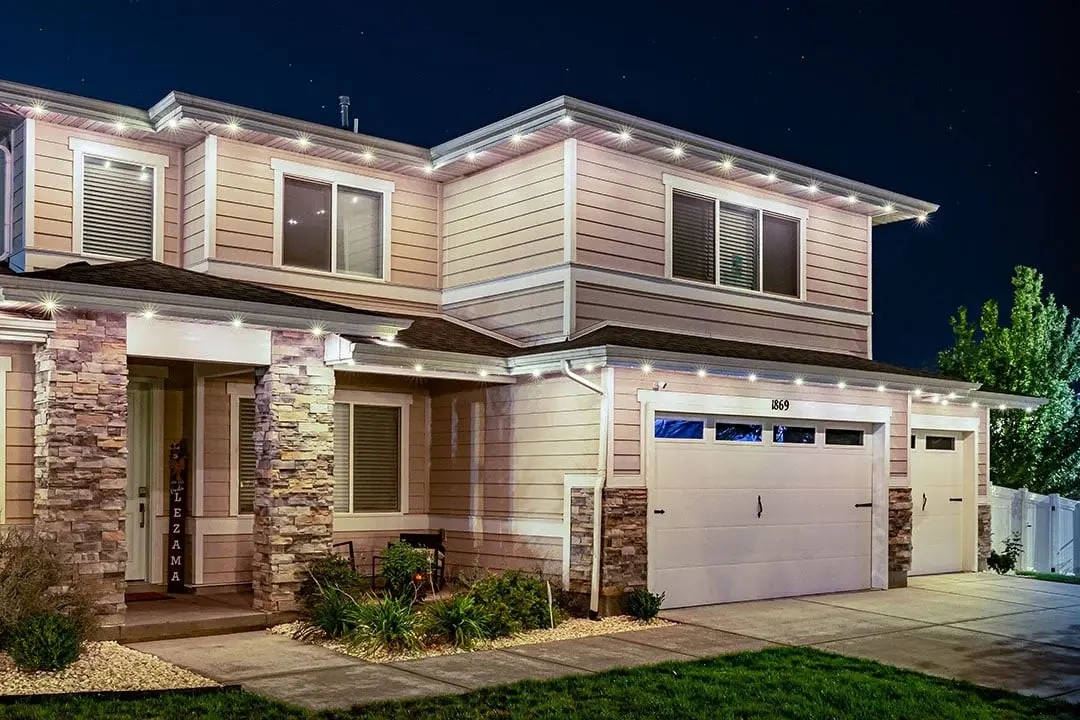 Two-story home at night with white accent lights along the eaves