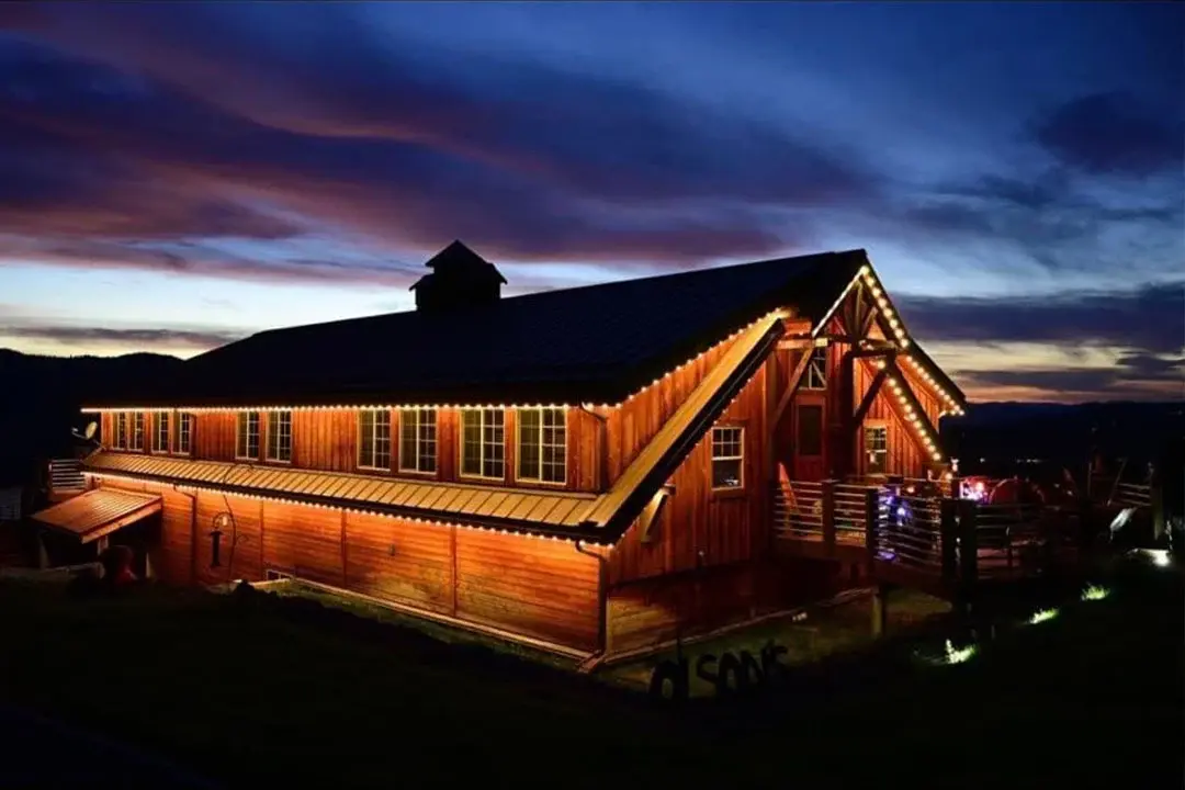 Barn-style building at night with warm white roofline lights