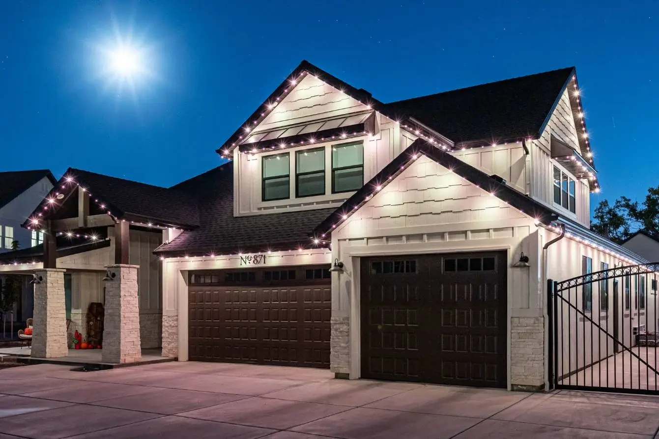 Two-story home at night with cool white roofline lights